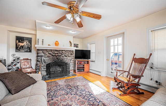 living room with ceiling fan, light hardwood / wood-style floors, a fireplace, and a baseboard radiator