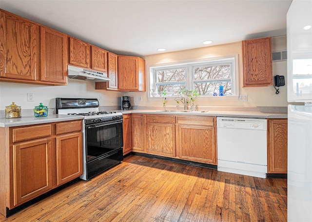 kitchen featuring white appliances, dark wood-type flooring, and sink