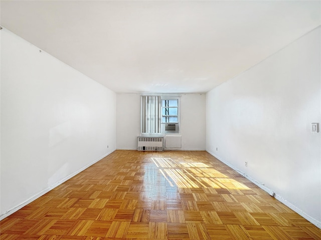 spare room featuring cooling unit, radiator, and light parquet floors