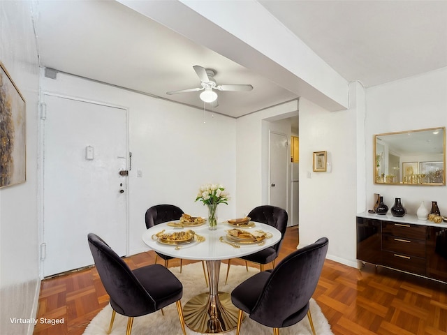 dining space with ceiling fan and dark parquet flooring