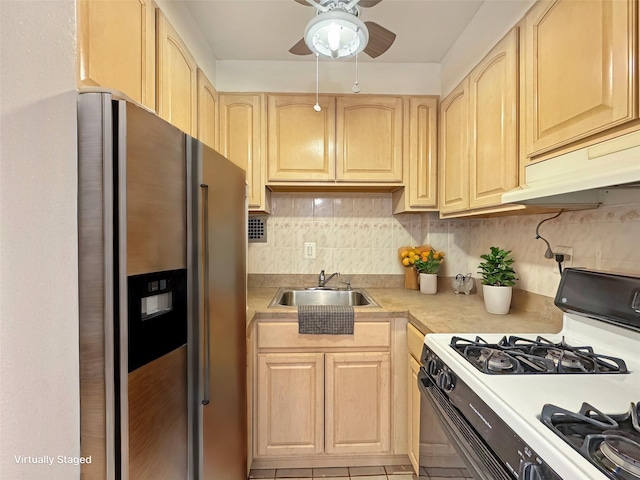 kitchen with backsplash, sink, white gas range oven, stainless steel fridge, and light brown cabinetry