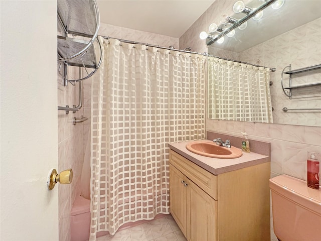 bathroom with vanity, toilet, tile walls, and walk in shower