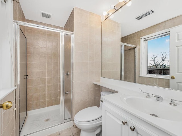 bathroom with tile patterned floors, vanity, toilet, and a shower with shower door