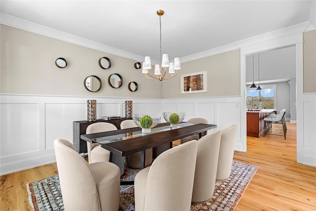 dining room featuring wood-type flooring, an inviting chandelier, and ornamental molding