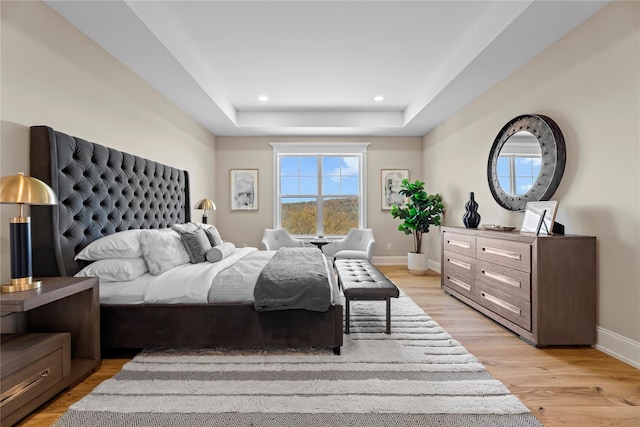 bedroom featuring a tray ceiling and light wood-type flooring