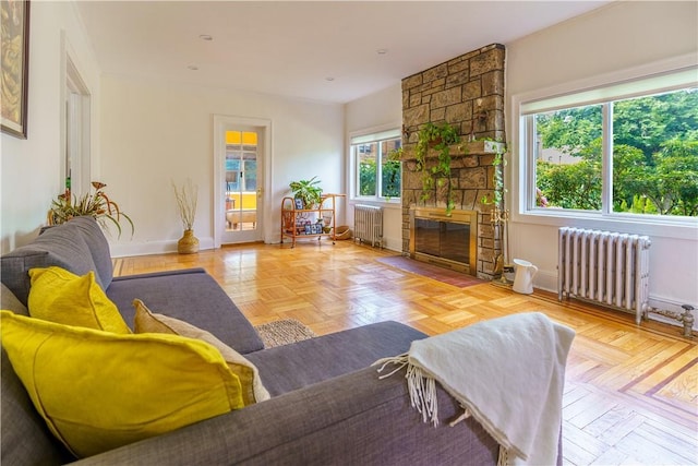 living room featuring light parquet floors, radiator heating unit, and a stone fireplace