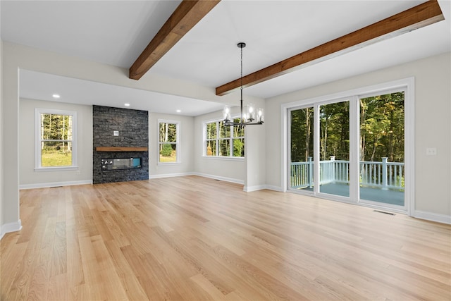 unfurnished living room featuring a fireplace, beam ceiling, light hardwood / wood-style floors, and an inviting chandelier