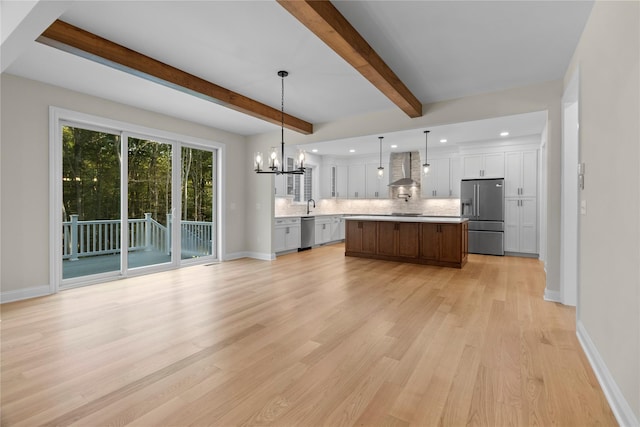 kitchen featuring wall chimney exhaust hood, stainless steel appliances, light hardwood / wood-style floors, a kitchen island, and hanging light fixtures