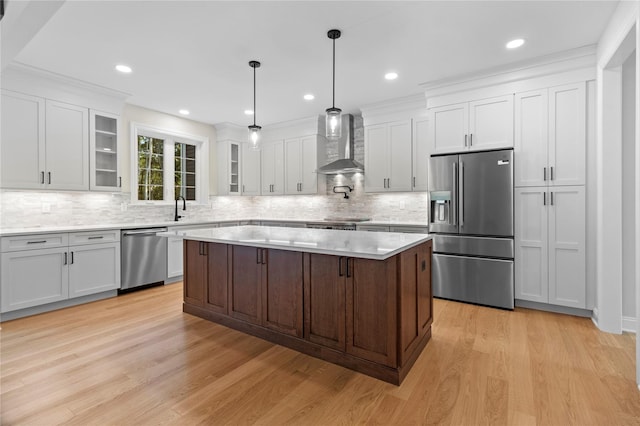 kitchen featuring wall chimney exhaust hood, light hardwood / wood-style floors, a kitchen island, and stainless steel appliances