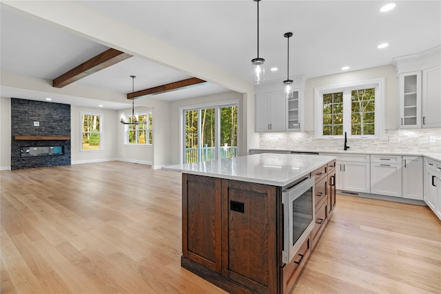 kitchen featuring white cabinets, a kitchen island, stainless steel microwave, and beamed ceiling