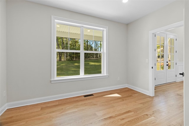 unfurnished room featuring french doors, a wealth of natural light, and light hardwood / wood-style flooring