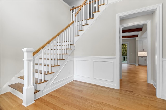 stairs with beam ceiling and hardwood / wood-style flooring