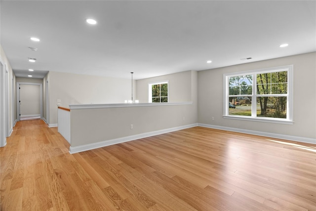 empty room featuring a notable chandelier and light hardwood / wood-style floors