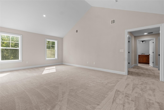 carpeted empty room with high vaulted ceiling