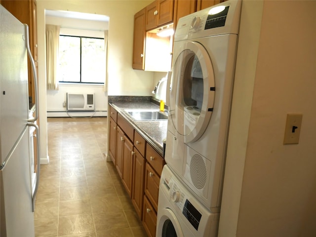 clothes washing area featuring a baseboard radiator, a wall unit AC, stacked washer / dryer, and sink