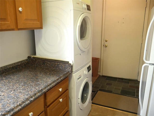 laundry room featuring cabinets and stacked washer / dryer