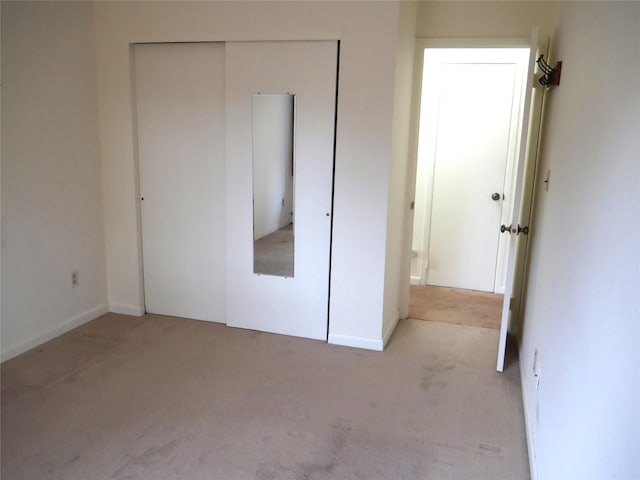 unfurnished bedroom with light carpet and a closet