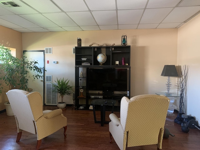 living room featuring a paneled ceiling and dark wood-type flooring