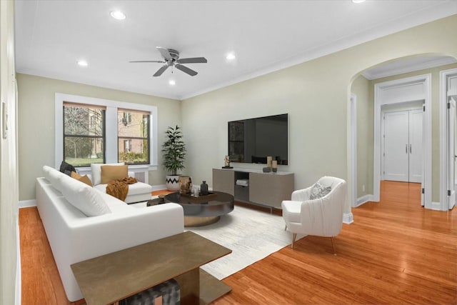 living room featuring light hardwood / wood-style flooring, ornamental molding, and ceiling fan