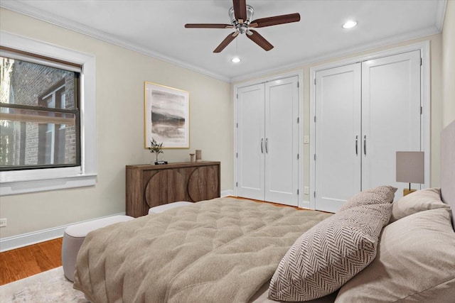 bedroom with ceiling fan, ornamental molding, light wood-type flooring, and two closets