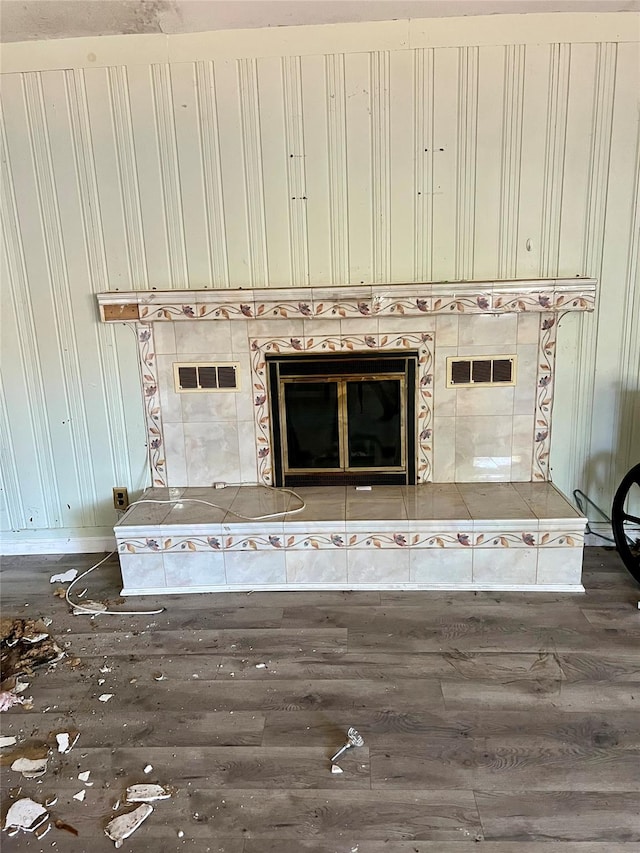 interior details featuring a tiled fireplace and wood-type flooring