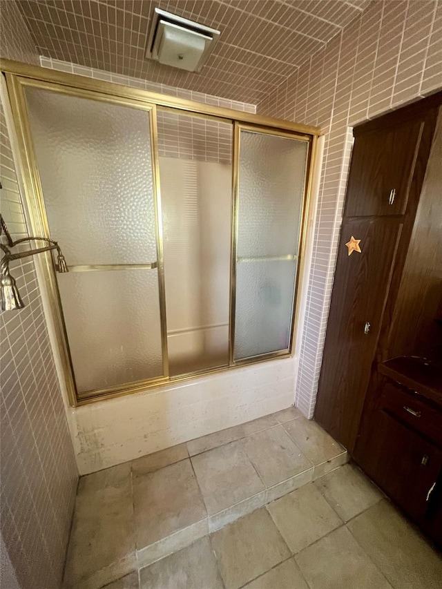 bathroom with tile patterned floors, tile walls, and enclosed tub / shower combo