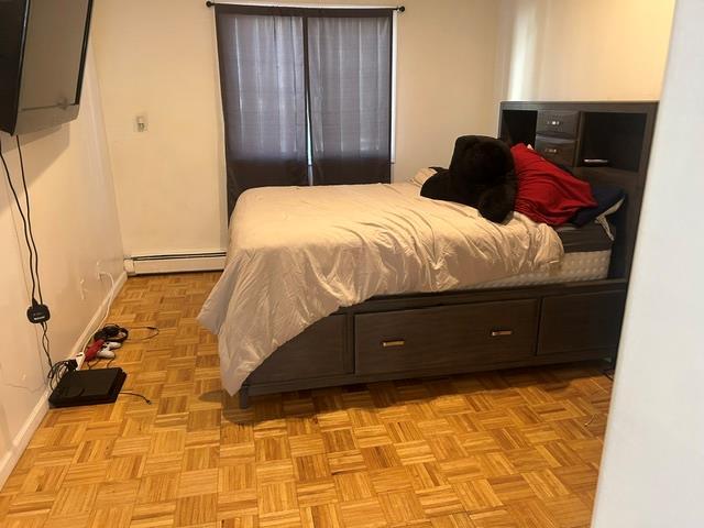 bedroom featuring light parquet floors and a baseboard heating unit