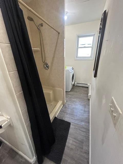 bathroom featuring baseboard heating, a shower with curtain, wood-type flooring, and independent washer and dryer