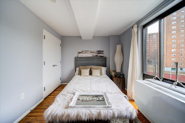 bedroom featuring beam ceiling and hardwood / wood-style flooring