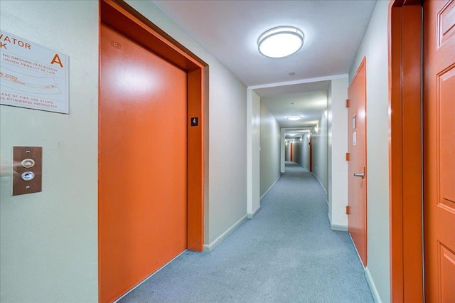 hallway with light colored carpet and elevator