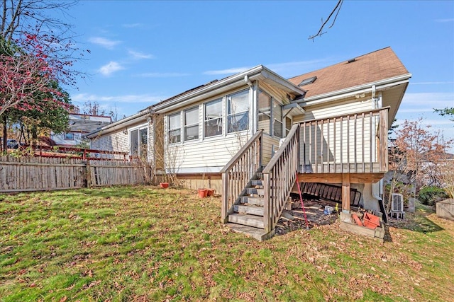 rear view of house featuring a wooden deck and a lawn