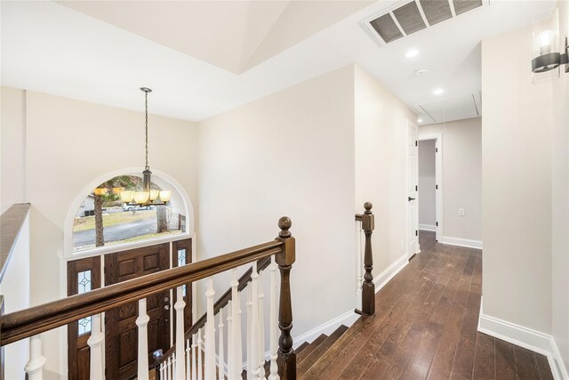 hallway with dark hardwood / wood-style flooring and a notable chandelier