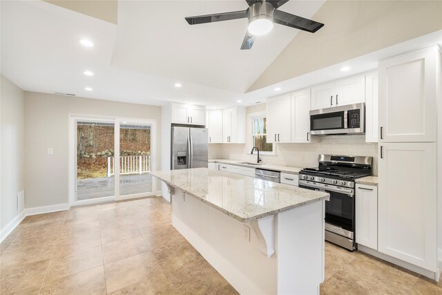 kitchen with white cabinets, a kitchen breakfast bar, vaulted ceiling, appliances with stainless steel finishes, and a kitchen island