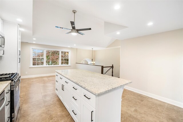 kitchen featuring ceiling fan, white cabinetry, light stone countertops, a kitchen island, and appliances with stainless steel finishes