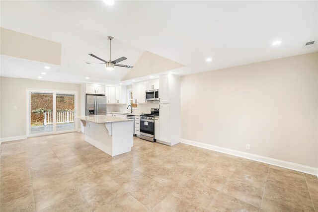 kitchen featuring a breakfast bar, a center island, lofted ceiling, white cabinets, and stainless steel appliances