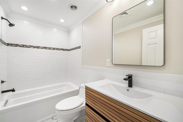 full bathroom with vanity, toilet, ornamental molding, and tiled shower / bath combo