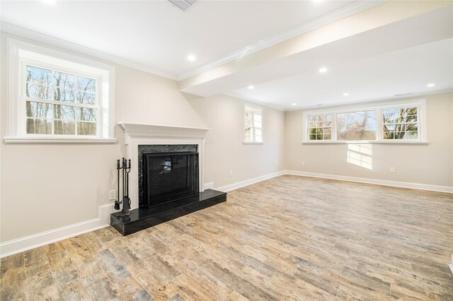 unfurnished living room featuring a high end fireplace, light hardwood / wood-style floors, and crown molding