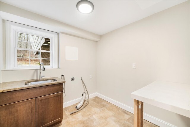 clothes washing area with cabinets and sink