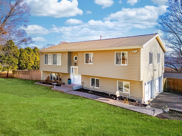 rear view of property featuring a lawn and a garage