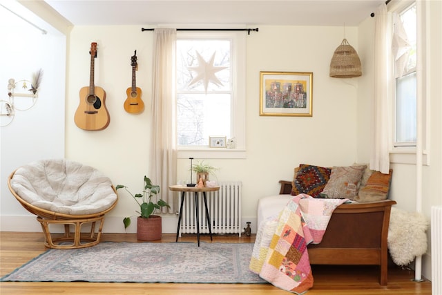 living area with a wealth of natural light, hardwood / wood-style flooring, and radiator