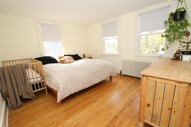 bedroom featuring radiator and light hardwood / wood-style flooring