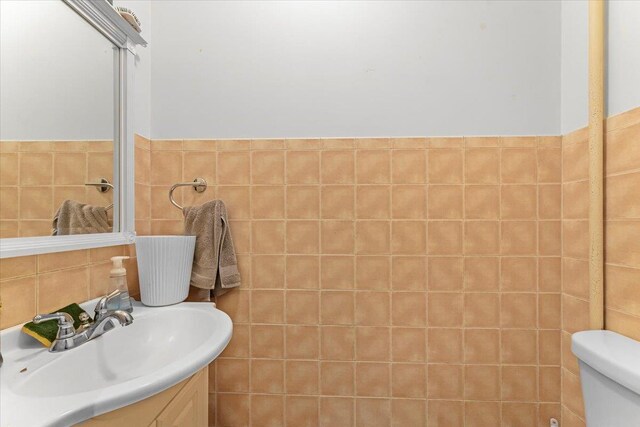 bathroom featuring vanity, toilet, and tile walls