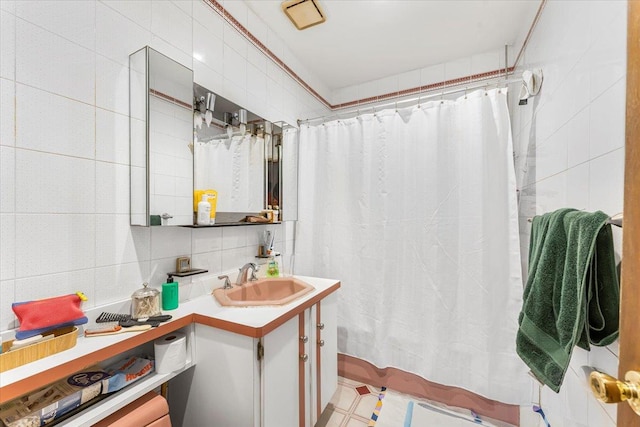 bathroom with vanity, tile walls, curtained shower, and backsplash