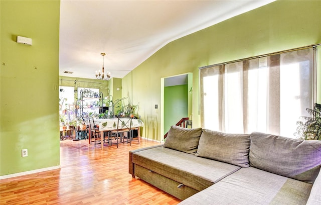 living room featuring hardwood / wood-style floors, a notable chandelier, and lofted ceiling