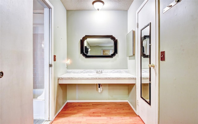 hall featuring a textured ceiling, light hardwood / wood-style flooring, and sink