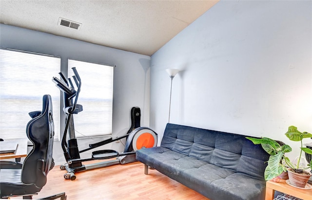 workout room featuring wood-type flooring and a textured ceiling