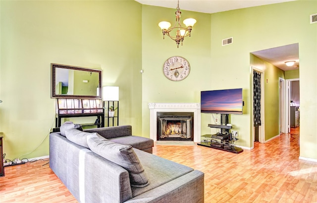 living room featuring high vaulted ceiling, wood-type flooring, and an inviting chandelier