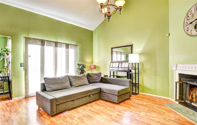 living room with high vaulted ceiling, a chandelier, and light wood-type flooring