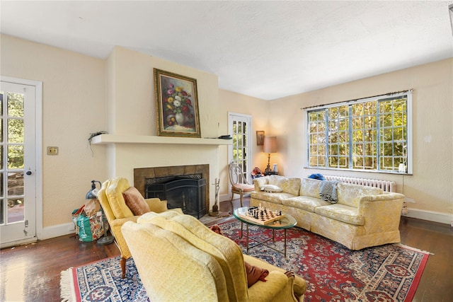 living room featuring radiator heating unit, dark wood-type flooring, and a tiled fireplace