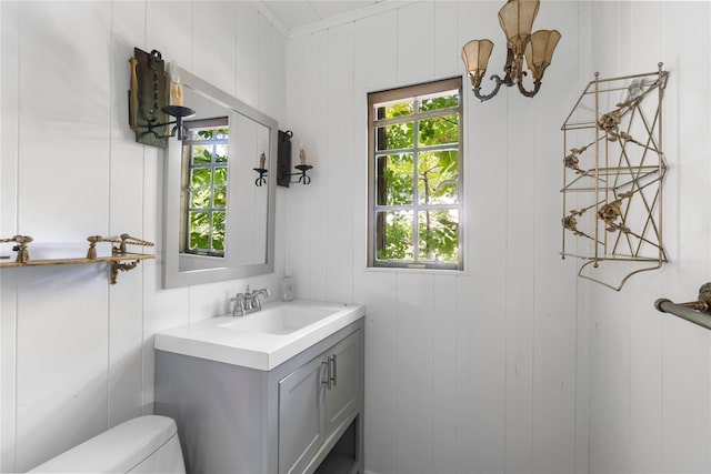 bathroom with wooden walls, vanity, ornamental molding, and toilet